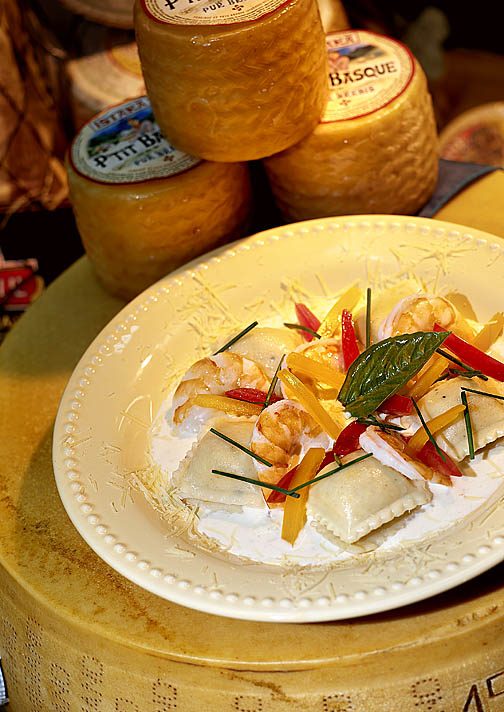 Plated vegetables in front of wheels of cheese