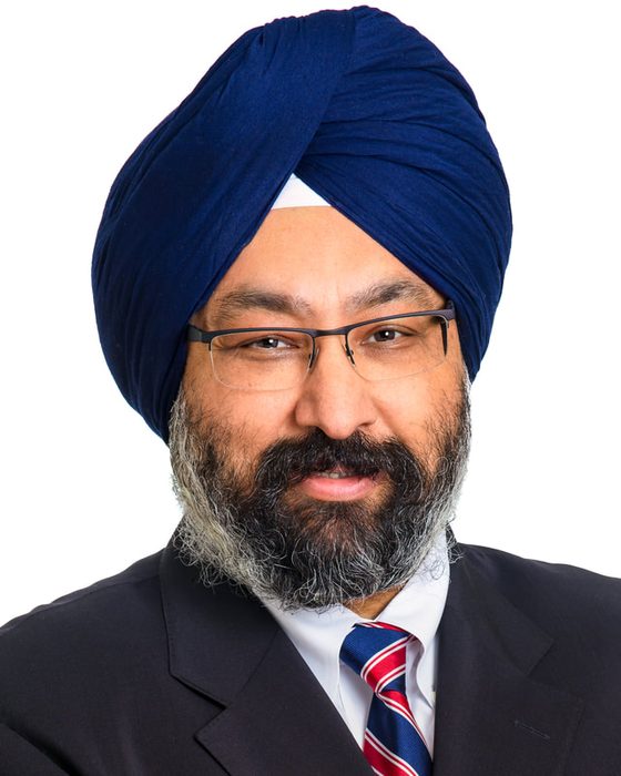 Corporate headshot of a man in a blue turban on white