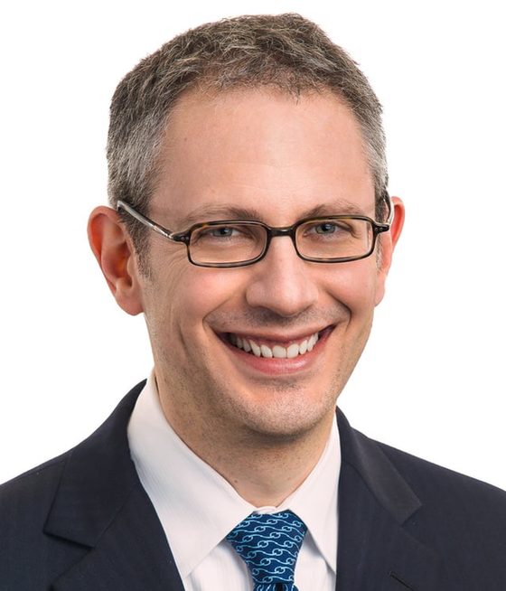 Corporate headshot of a smiling man in a suit on white