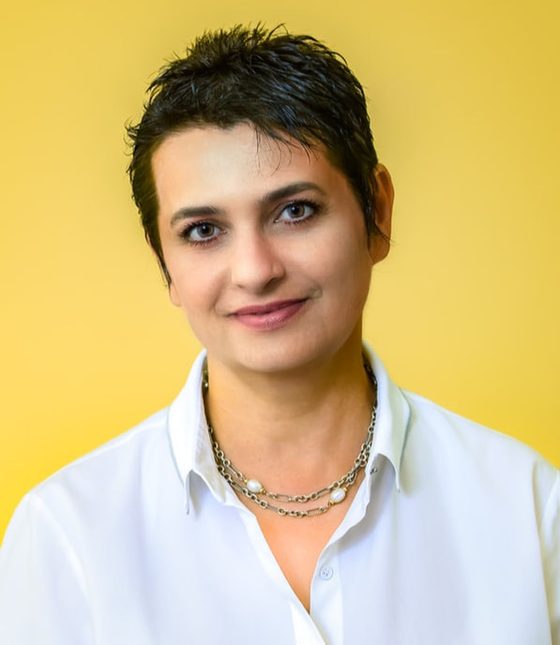 Portrait of a woman in a white shirt against a yellow wall