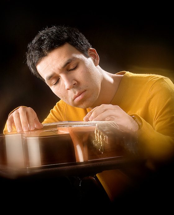 Man in a yellow sweater lit in warm, dramatic light