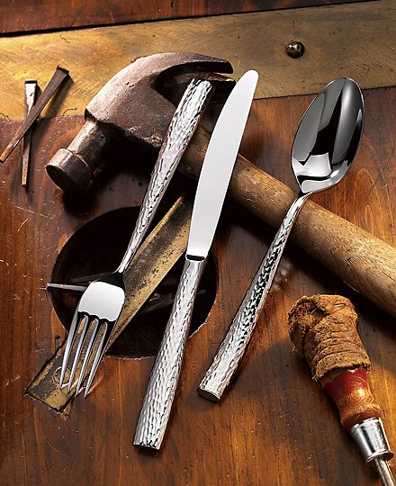 Hammered cutlery arranged with old tools on wood